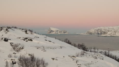 Isla-Haaja-Cubierta-De-Nieve-En-El-Horizonte-Sobre-El-Fiordo,-Cielo-Rosado-Del-Atardecer