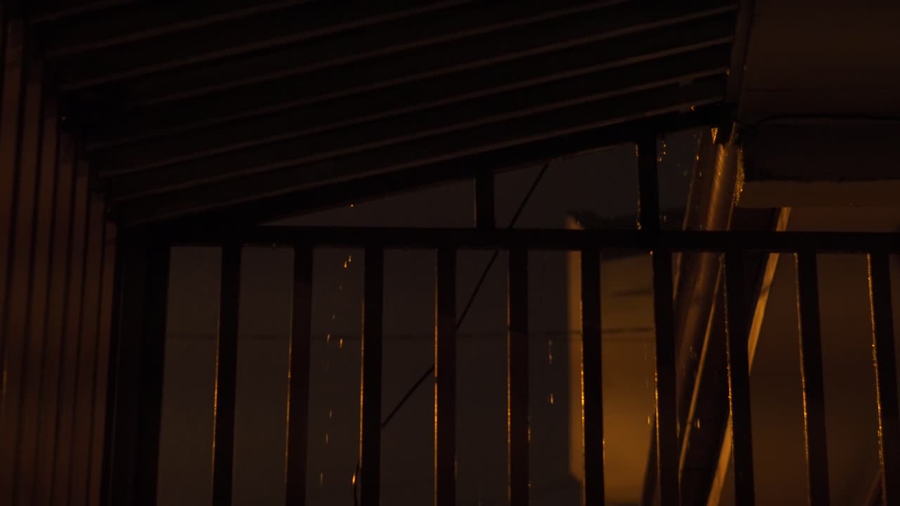 Chuva à noite através das grades do portão.