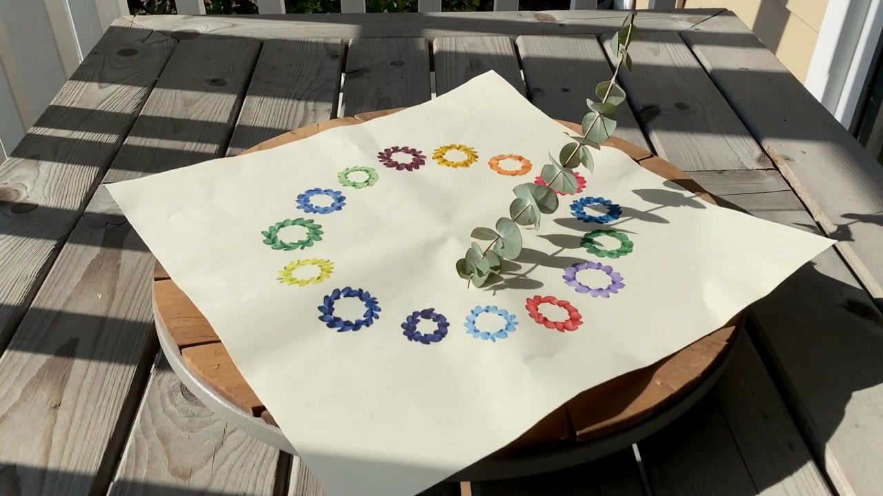 Turning platform moving pale square paper on balcony, eucalyptus sprig sweeping across stamped ring