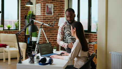 interracial creative team programing code on a laptop and debugging