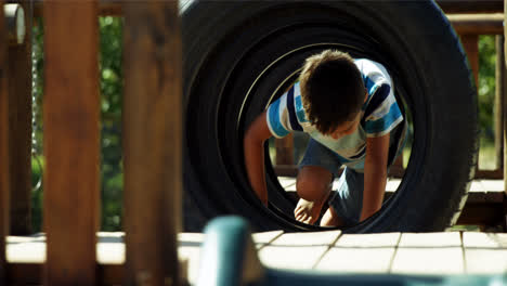 Schoolboy-crawling-through-tyres-in-playground