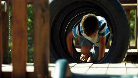 Schuljunge-Kriecht-Durch-Reifen-Auf-Dem-Spielplatz