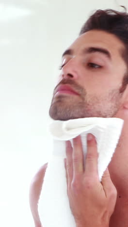 hombre limpiándose la cara frente al espejo