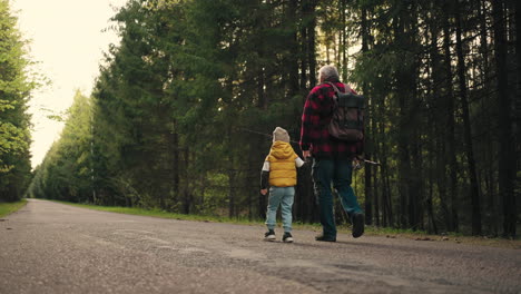 divertido niño pequeño y abuelo están caminando a pescar en el lago del bosque en la mañana de fin de semana viejo pescador y su nieto