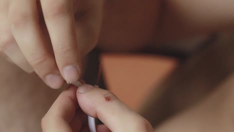 close up to hands stripping the insulation of an electrical cable to expose the copper conductors using a box cutter utility knife