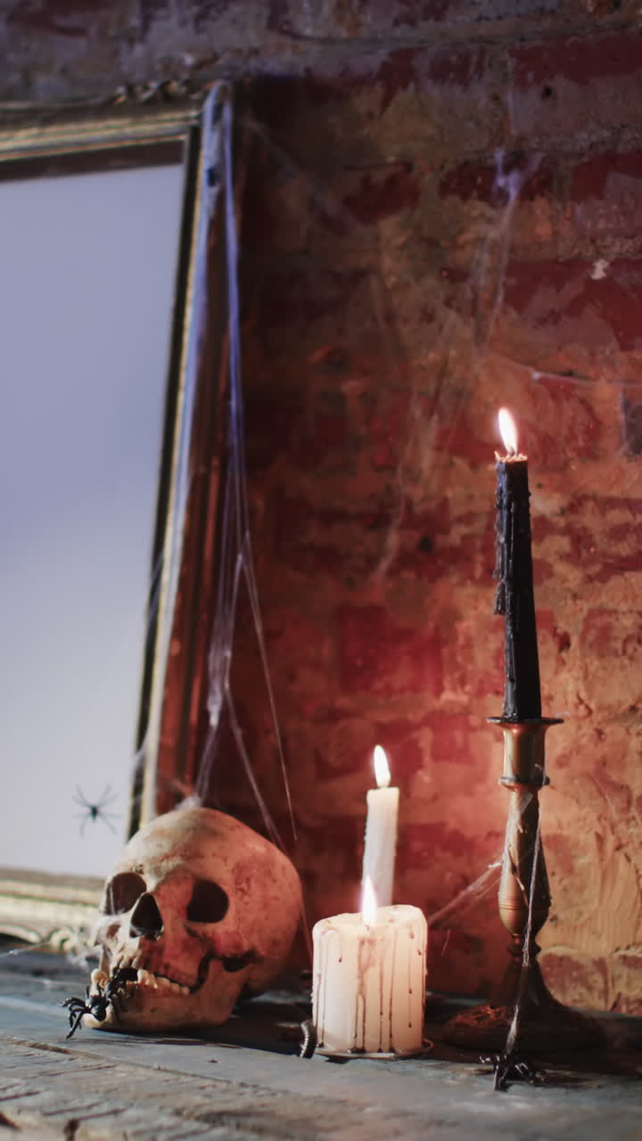 Vertical video of stack of frame with spider web, skull and candles on brick wall background