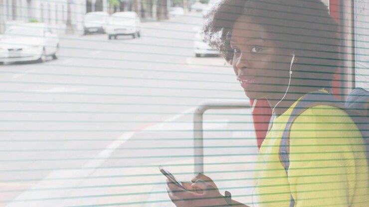 Woman waiting at bus shelter, scrolling phone, tapping screen, lifting head, smiling toward camera