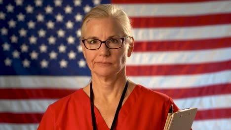 medium tight portrait of a healthcare nurse with clipboard walking towards camera shaking her head with an out of focus american flag