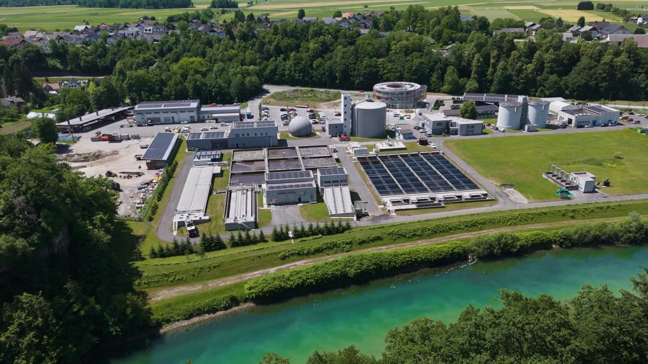 The picture shows a large wastewater treatment plant with settling tanks and filtration systems