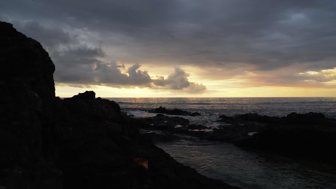 The stunning sunset view from the rocky shores of the Fiji islands - wide shot
