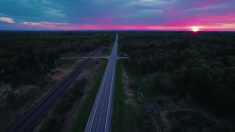 sunset drone aerial of forest-lined highway in wisconsin