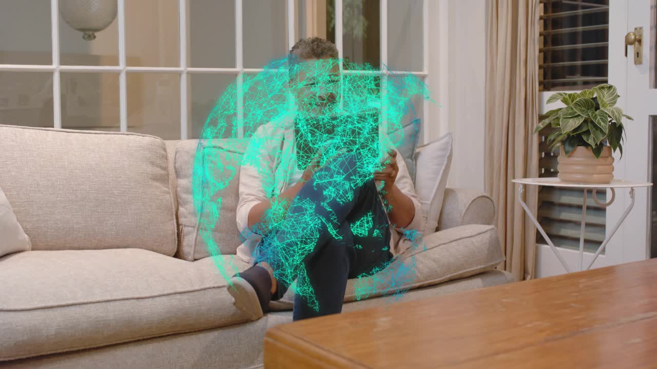 Uomo che tocca un tablet a casa, creando un ologramma color petrolio di un globo in espansione, rotazione ed esplorazione di dati tecnologici
