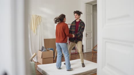 couple dancing on mattress in new apartment