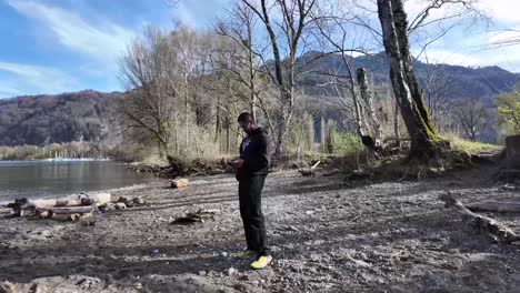 hombre operando el dron afuera en el bosque cerca del lago, suiza