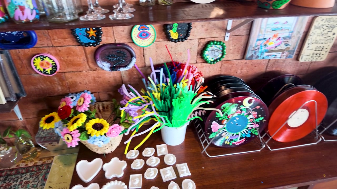 Camera pans across vibrant felt flowers and clay crafts on a wooden workshop table.