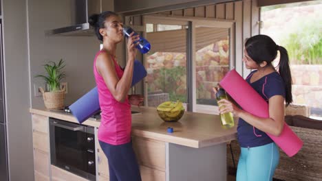 video de felices amigas diversas sosteniendo esteras de yoga y hablando en casa