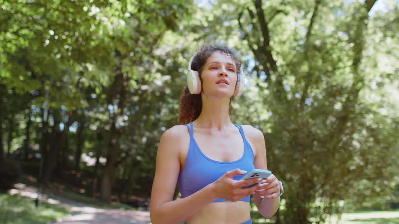 atleta, atleta deportiva, mujer caminando, usando auriculares, escuchando música desde su teléfono inteligente
