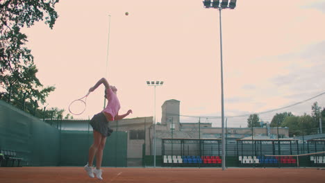 low angle view in slow-motion of a young female tennis player preparing to serve a tennis match. a woman athlete is powerfully hitting a ball during sports practice. commercial use footage