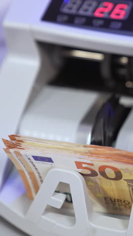 electronic calculations of euros. automatic equipment for counting paper money. fifty euro banknotes in a modern counting machine. vertical video
