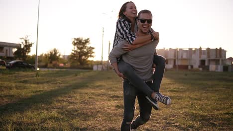 Glückliche-Junge-Männer,-Die-Frauen-Im-Park-Huckepack-Fahren