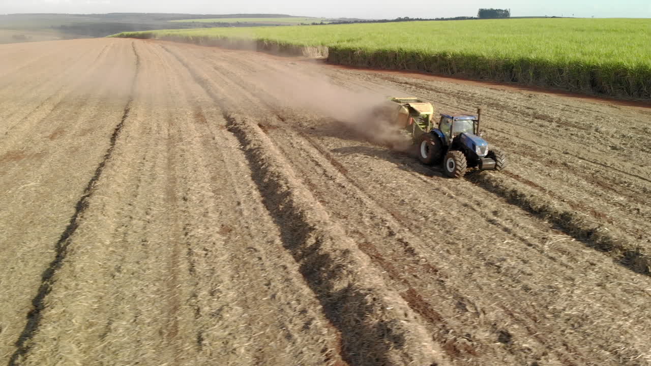 Agricultural Tractor Working in Dusty Sugarcane Field