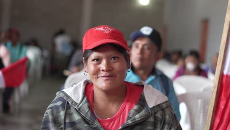 portrait of a woman in a red cap at an indoor event with a peruvian flag