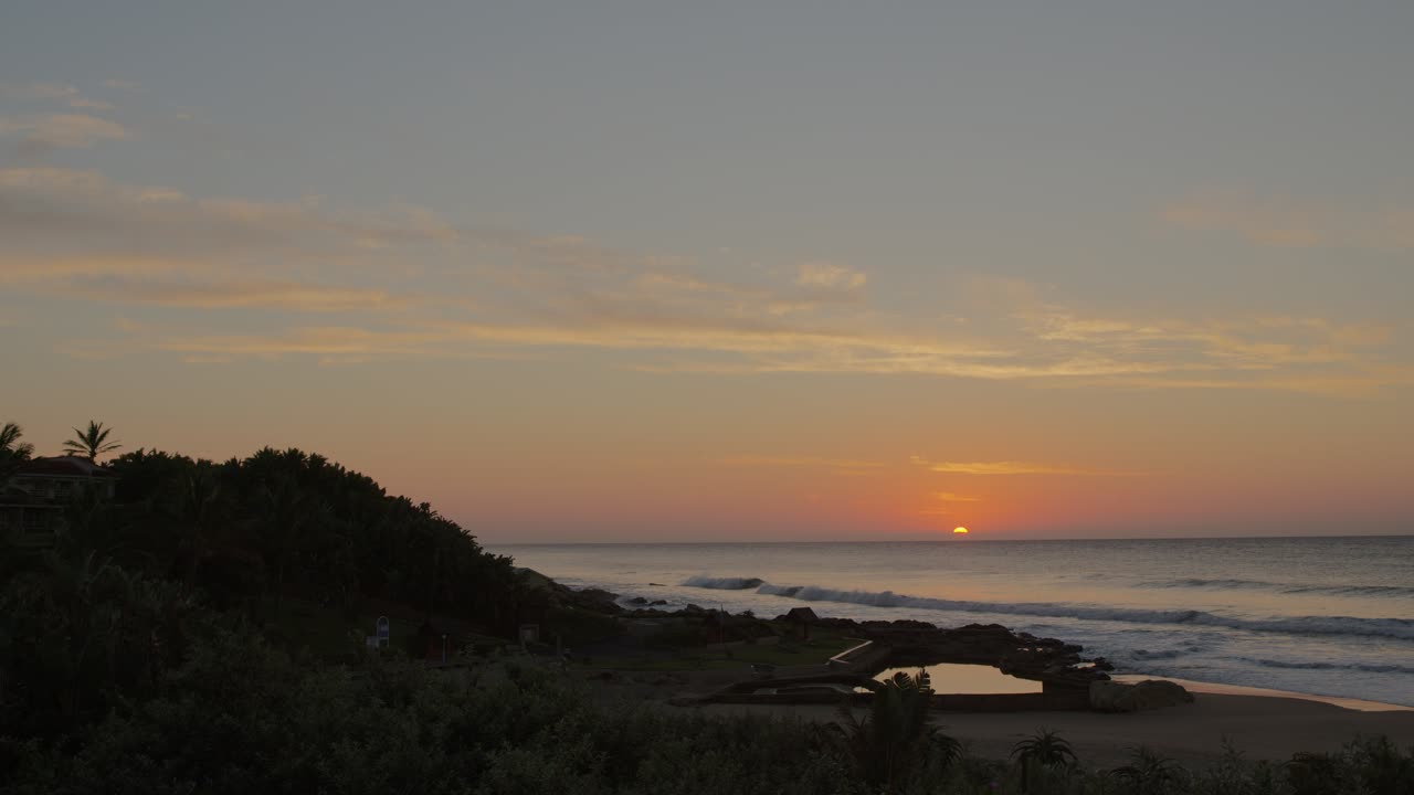 Time-lapse of a sunrise over the ocean, capturing the serene transition from dawn to day as the sun ascends above the horizon, illuminating the water with soft, golden light.