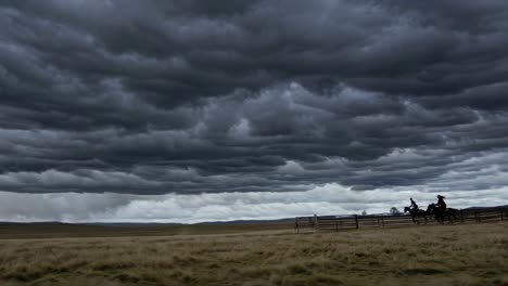cowboys and cowgirls riding horses under a stormy sky