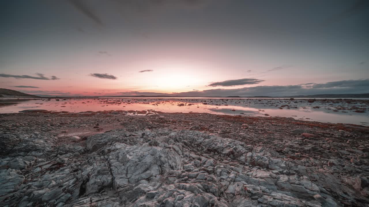 las nubes oscuras se mueven rápidamente sobre el cielo al atardecer y sobre la costa rocosa del fiordo en un video de time-lapse