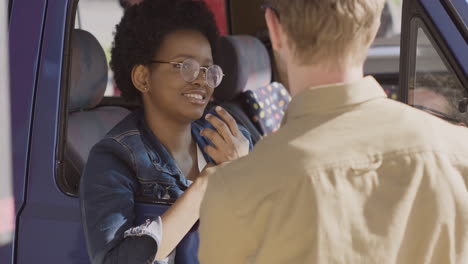 an young woman talks with a guy up in her caravan