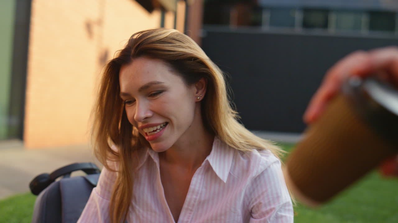 una mujer hermosa bebiendo café en un parque de la ciudad de primer plano. una chica sonriente habla con un amigo.