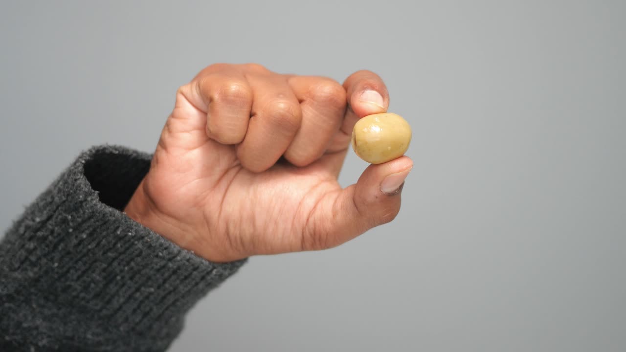 Hand Holding a Single Green Pitted Olive