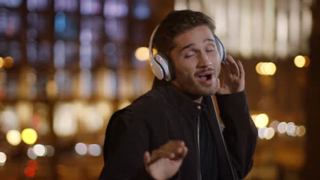 positive man singing in headphones on dark street. happy guy listening music.