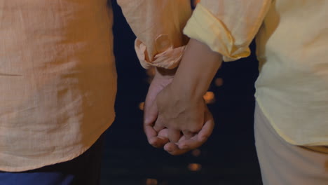 senior couple holding hands by the sea at night