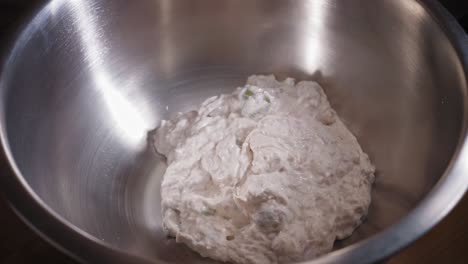 close-up view of adding tuna dressing and cooked pasta to a metal bowl - steady shot