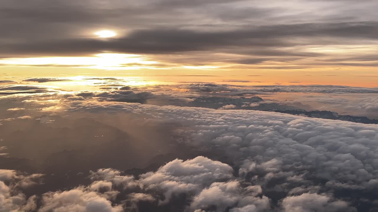 impresionante vista lateral aérea de una puesta de sol tomada desde una cabina de un avión mientras volaba sobre los alpes italianos y una capa de nubes en un vuelo real a 9000 m de altura