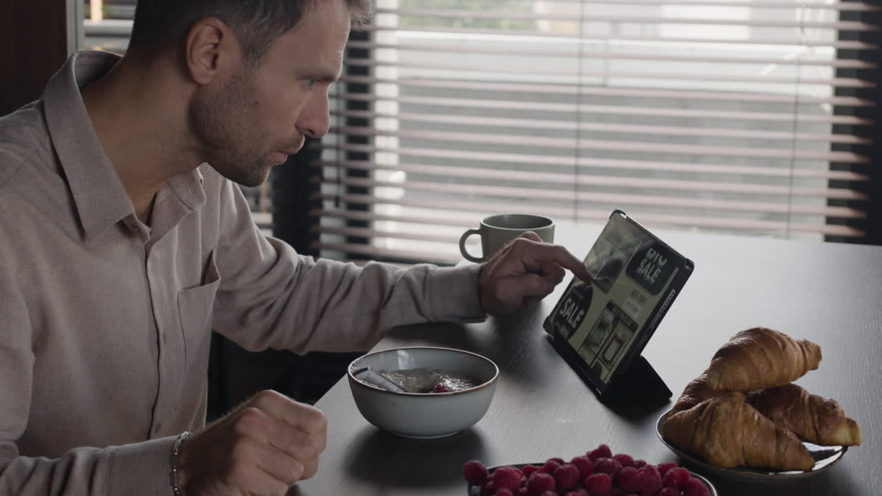 Man eating breakfast while using tablet