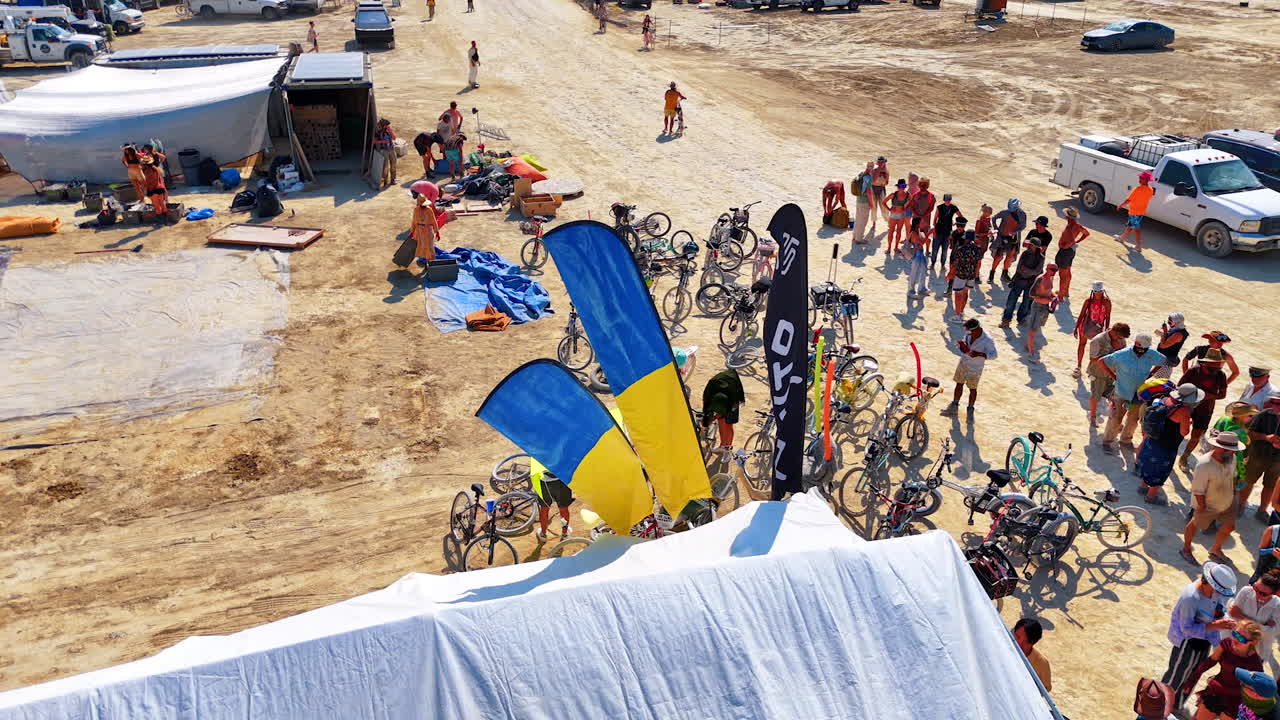 Line of people standing at the tent with Ukrainian flags. One of the locations in the Burning Man festival in the Black Rock Desert. Aerial view