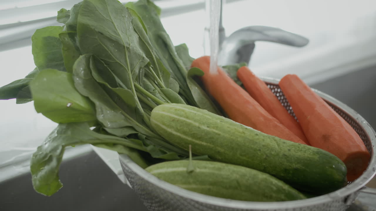 Carrot, Cucumbers and Greenery Washing in Colander in Sink