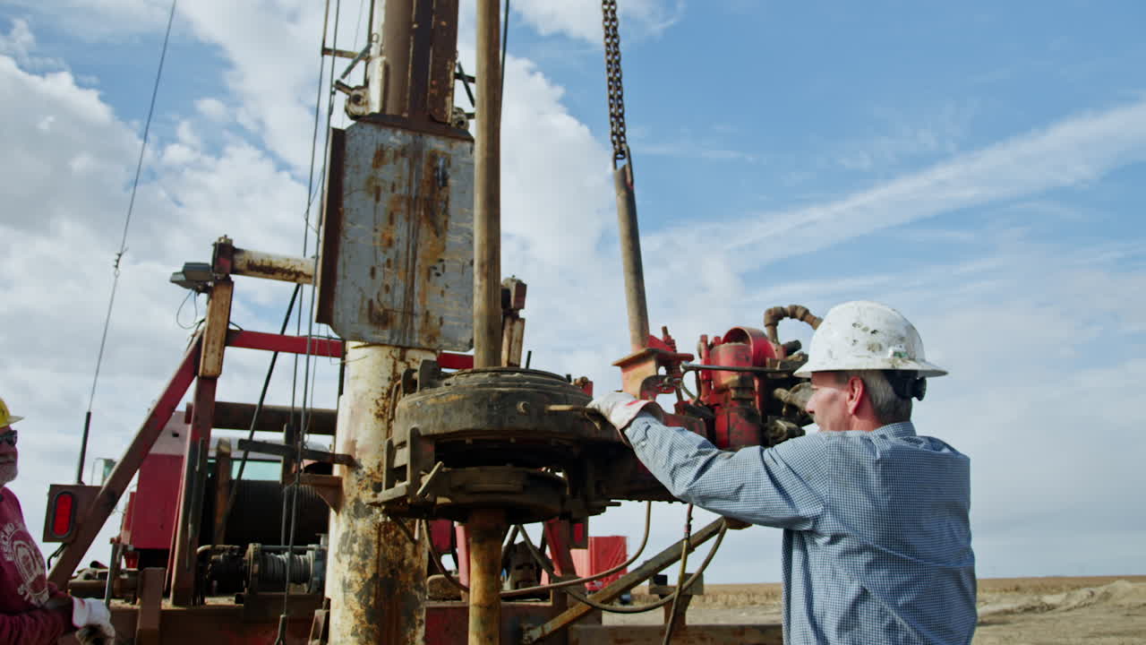 Men working at the machine with drilling equipment. Workers manage the technique for oil production.