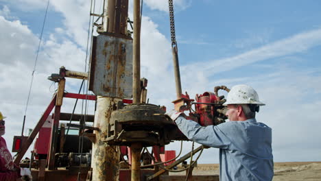 men working at the machine with drilling equipment. workers manage the technique for oil production.
