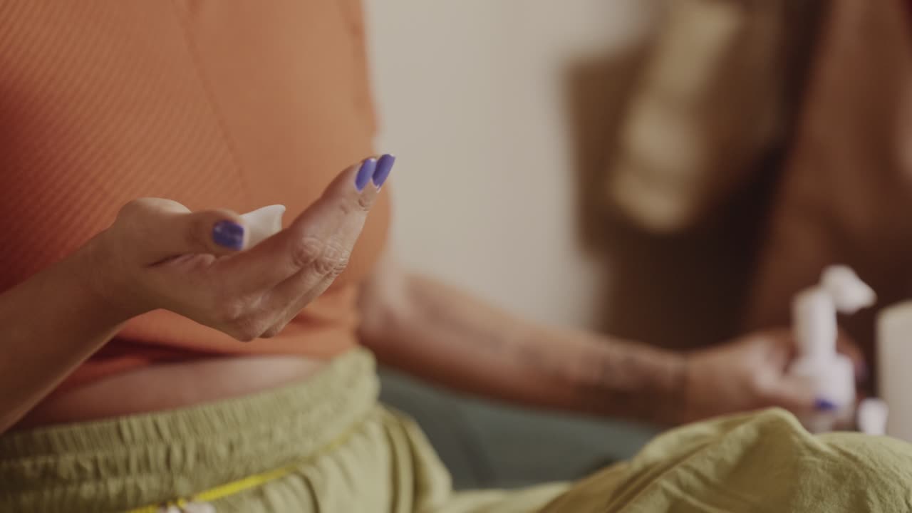 A person applying a white skincare product to their hands