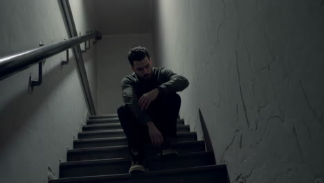 man sitting on stairs in a dark hallway