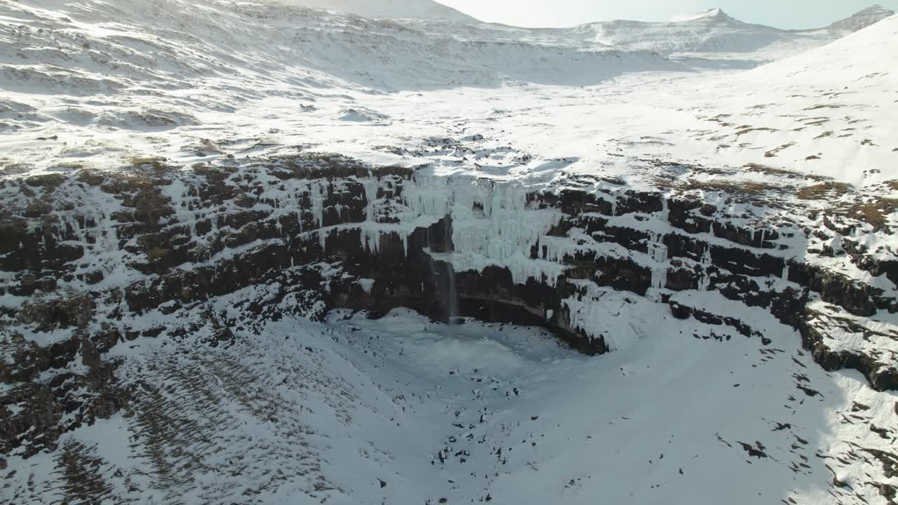 4k Aerial drone shot of frozen ice waterfall Foss&aacute;, the biggest and most famous waterfall on the Faroe Islands in a beautiful winter landscape covered in snow and iceon a sunny day