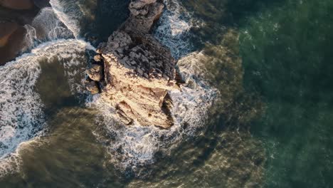 Eine-Top-down-luftaufnahme-Des-Ikonischen-Rabenfelsens-Von-El-Peñón-Del-Cuervo-Mit-Dem-Dunkelblauen-Wasser-Des-Alboran-meeres,-Das-In-Malaga,-Spanien,-Einstürzt