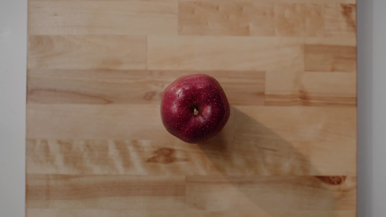 Et Red Delicious æble ligger på et skærebræt.