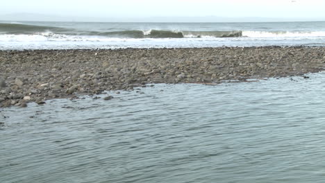 tilt up of water flowing out of the ventura river estuary and waves at surfers point in ventura california