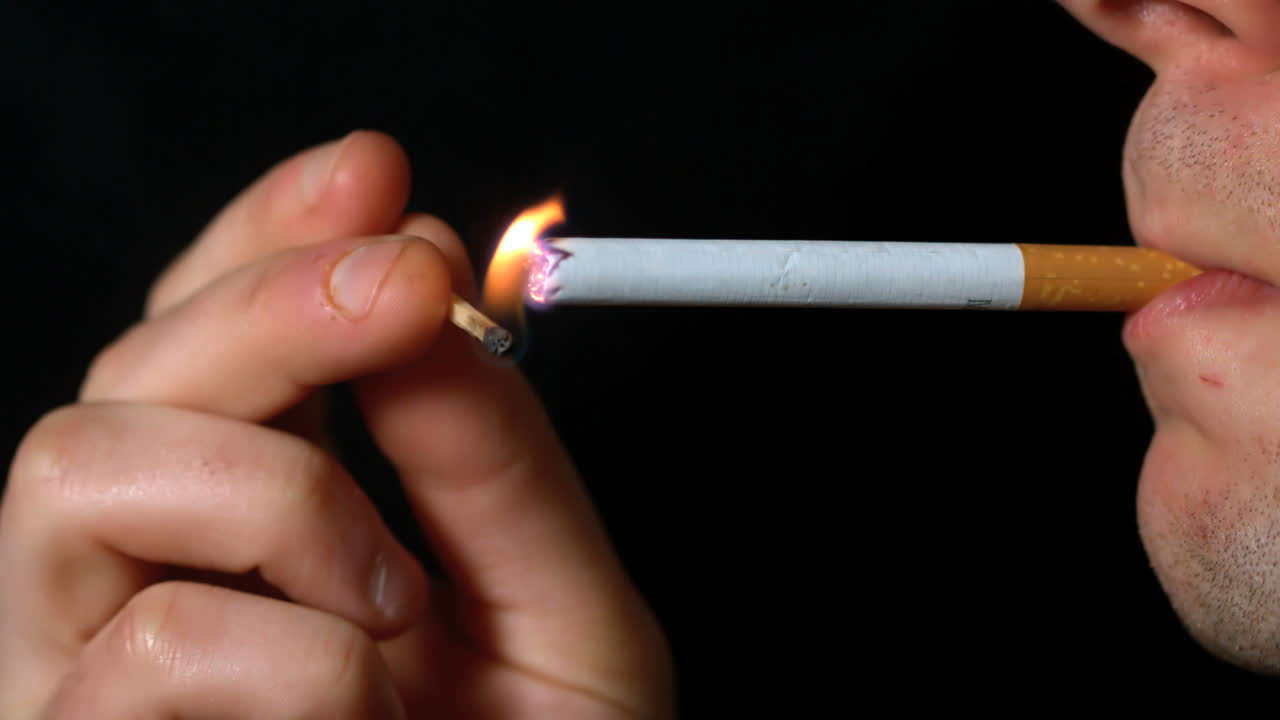 hombre encendiendo un cigarrillo con un fósforo