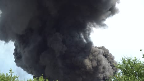 el humo negro se eleva hacia el cielo. un gran incendio químico en un edificio de fábrica. un espeso humo negro cubre el cielo. 4k