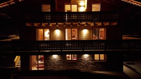 beautiful aerial of a lit up chalet with christmas lights at night in winter